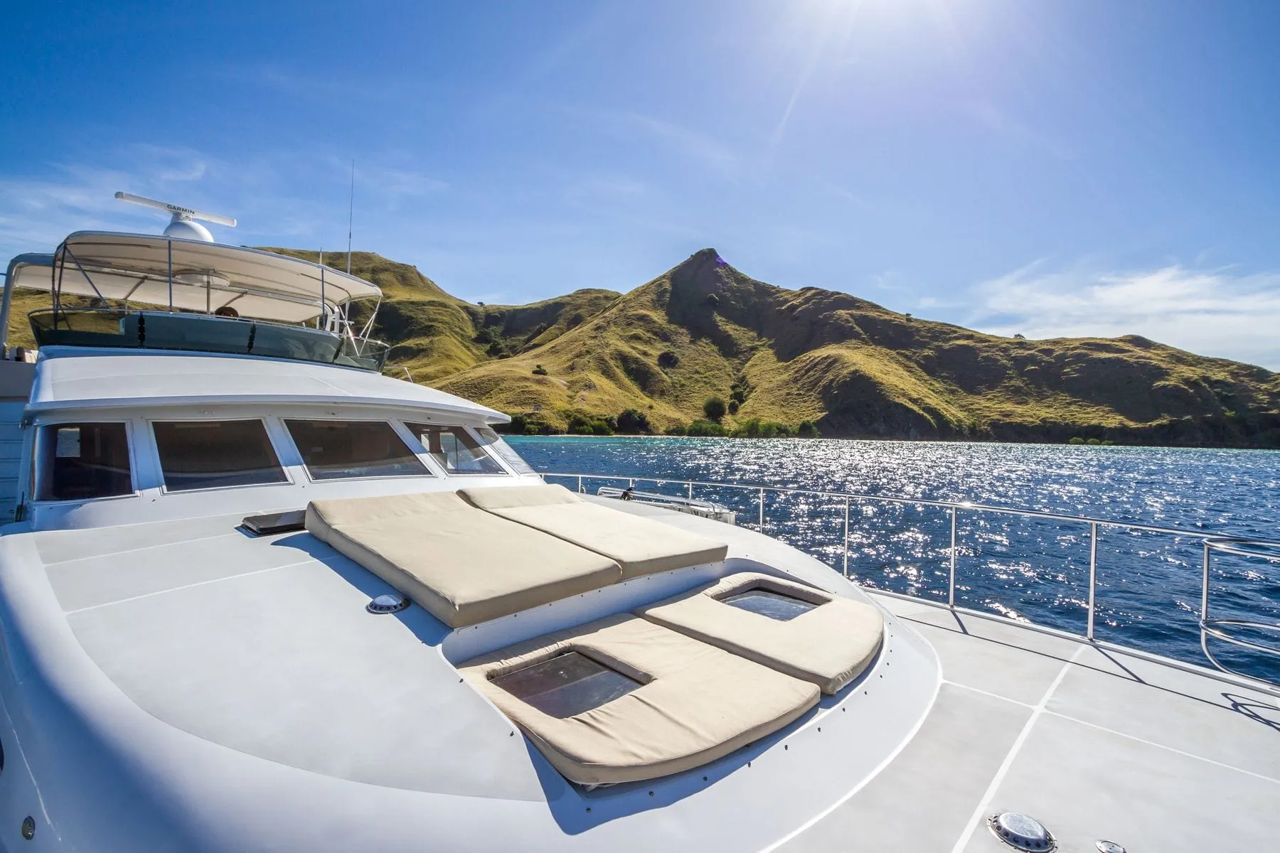 The foredeck of a motor yacht underway toward a green coastline