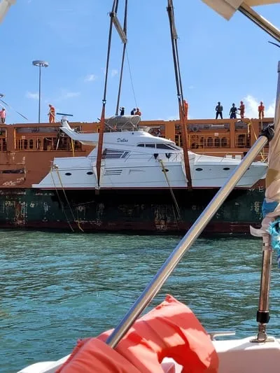 A yacht being lifted and loaded onto the deck of a transport ship